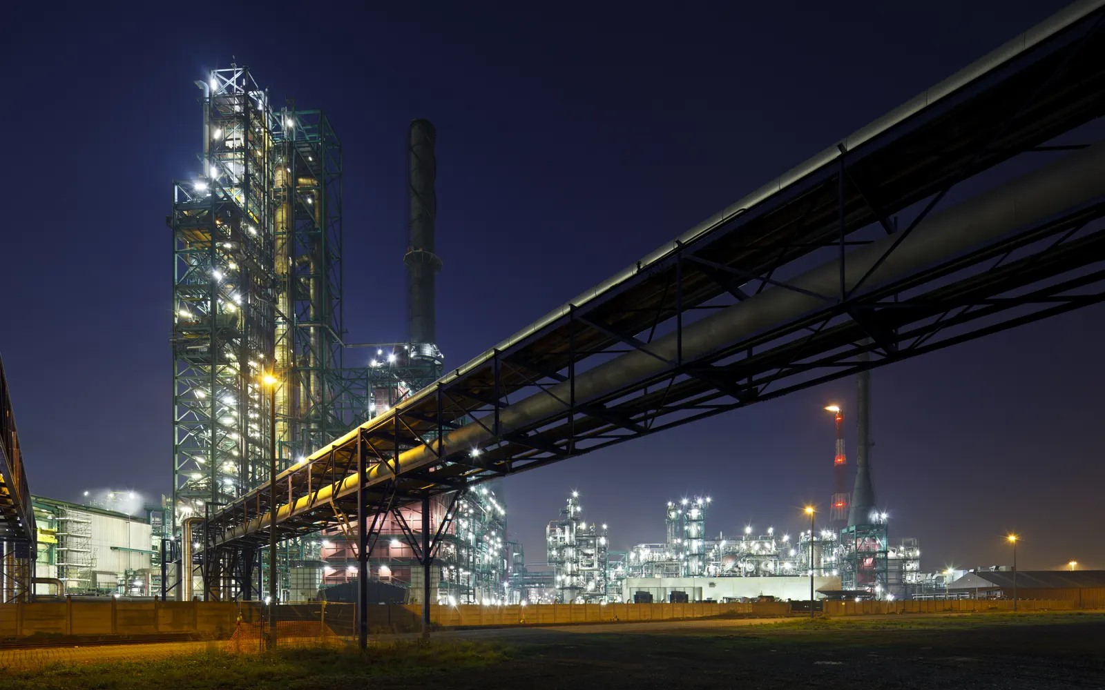 Process pipelines and refinery infrastructure illuminated at dusk